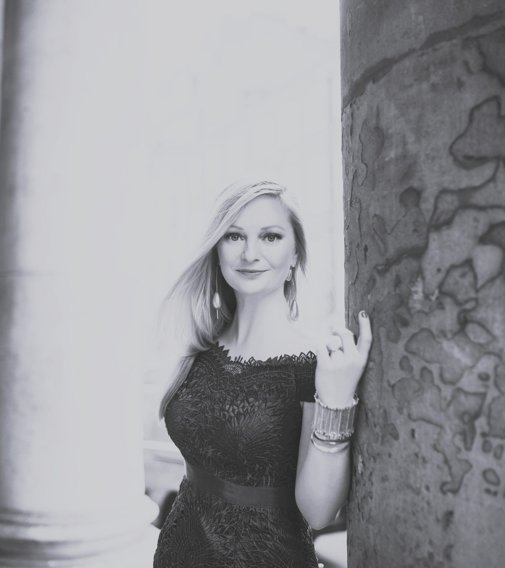 A woman leaning against a pillar.