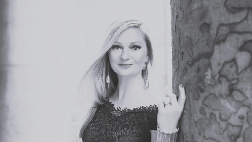 A woman leaning against a pillar.