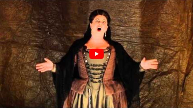 A woman in historical costume embodies one of the great mothers in opera, singing with arms outstretched.