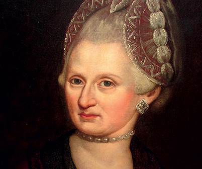 A painted portrait of a woman with pale skin, grey hair styled high, wearing a jewelled headpiece, a string of pearls around her neck, and a large square earring. She gazes forward with calm poise, evoking the elegance of women from Mozart’s era.