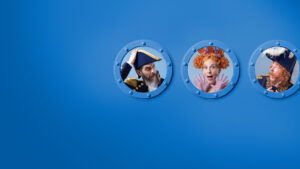 Three people in colourful, theatrical costumes and hats look out from round, blue ship portholes against a plain blue background. The left and right figures wear navy uniforms; the centre figure has red curly hair and a surprised expression.