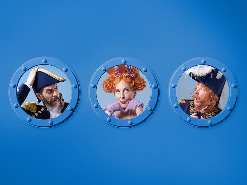 Three people in theatrical costumes look through separate round portholes against a blue background; two are dressed as naval officers and one as a woman with curly red hair and a purple dress.