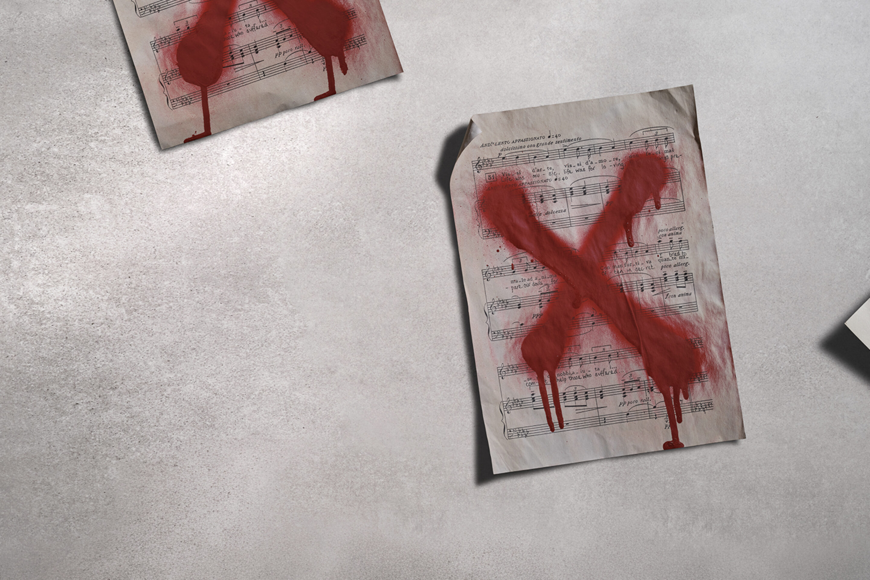 Three sheets of music lie on a grey surface, each marked with a large, red, painted X that appears to be dripping, suggesting rejection or censorship.