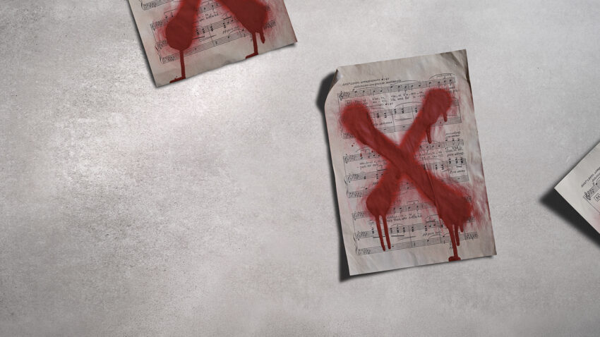 Three sheets of music lie on a grey surface, each marked with a large, red, painted X that appears to be dripping, suggesting rejection or censorship.