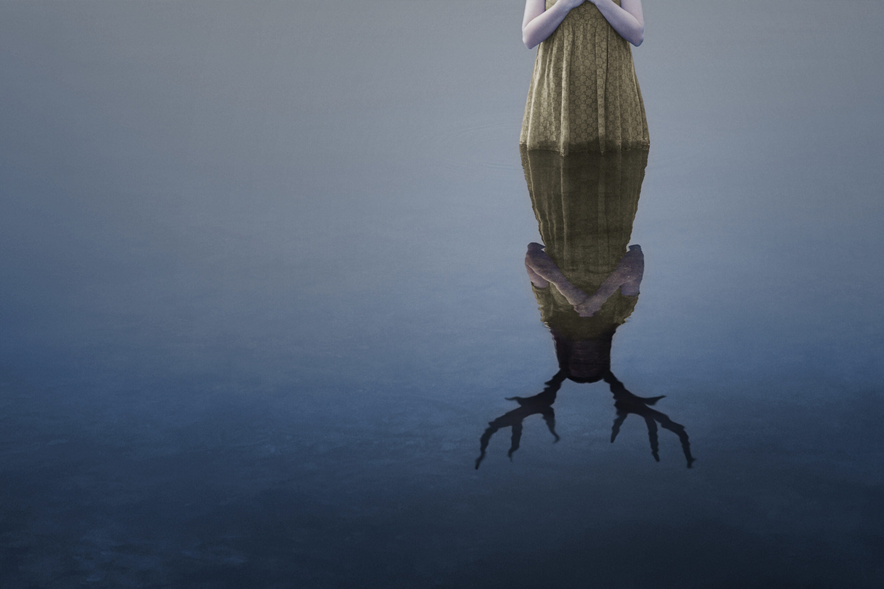 A person in a green dress stands by still water, hands clasped. Their reflection reveals antlers in place of a human head, evoking the haunting duality found in Iphigénie en Tauride.