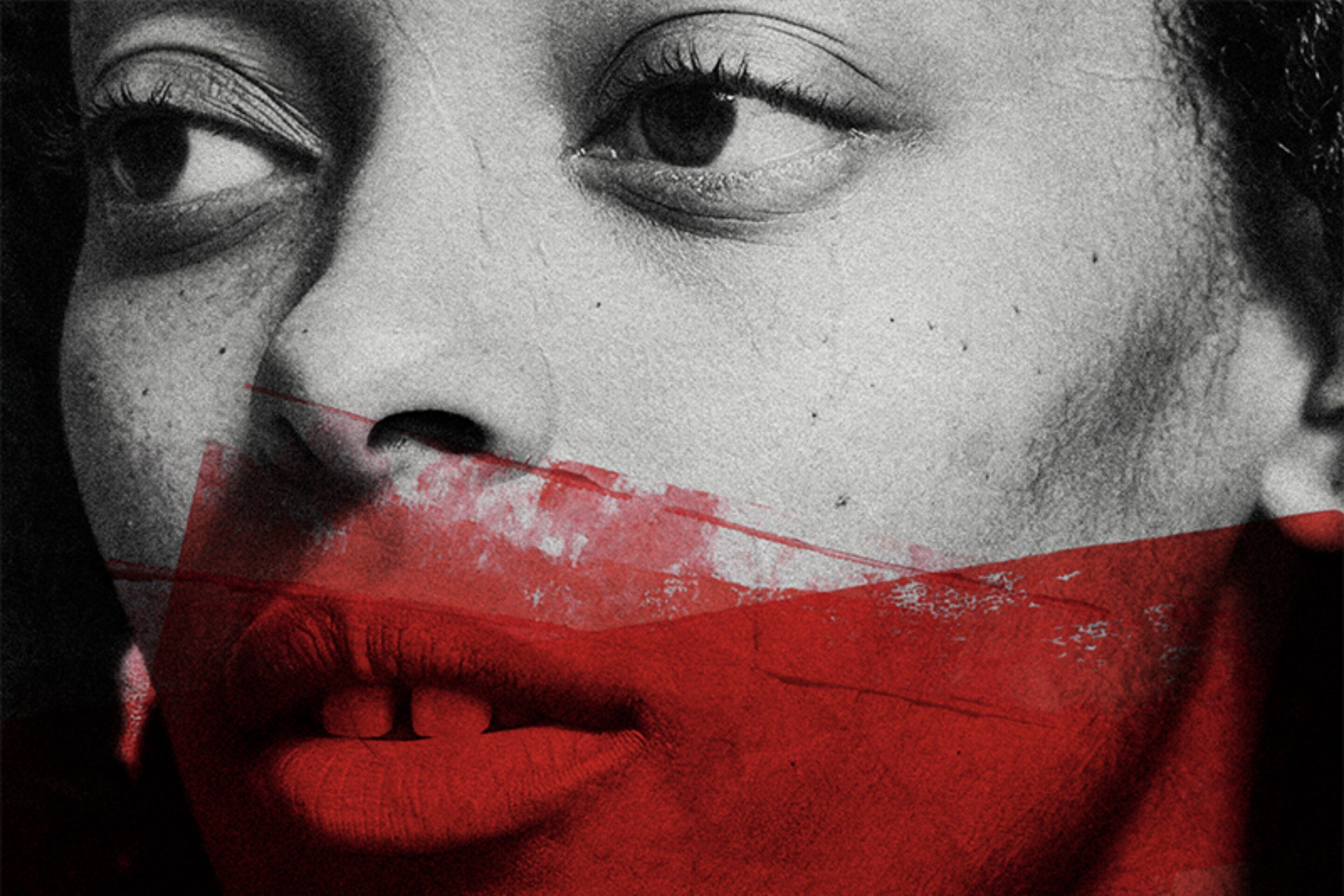 A greyscale close-up of a woman's face with a bold red paint streak across her mouth and lower face, evoking a sense of emotion and contrast.