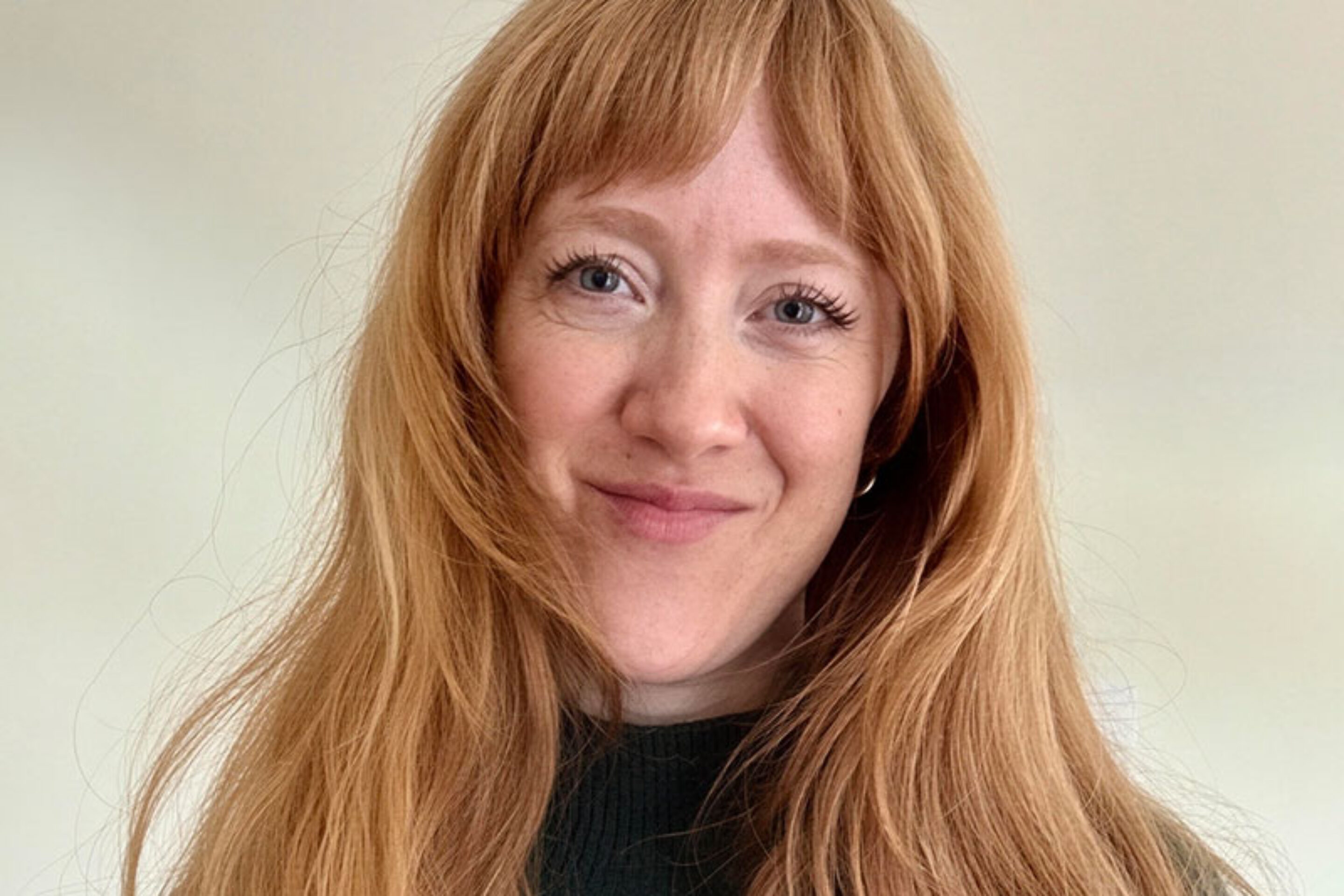 Amanda Tooke, a woman with long red hair and a fringe, smiles at the camera.