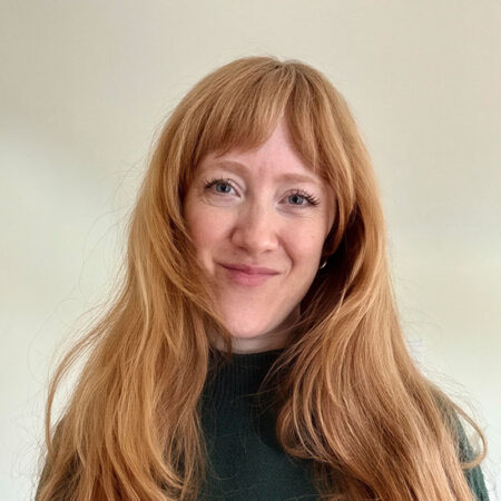 Amanda Tooke, a woman with long red hair and a fringe, smiles at the camera.