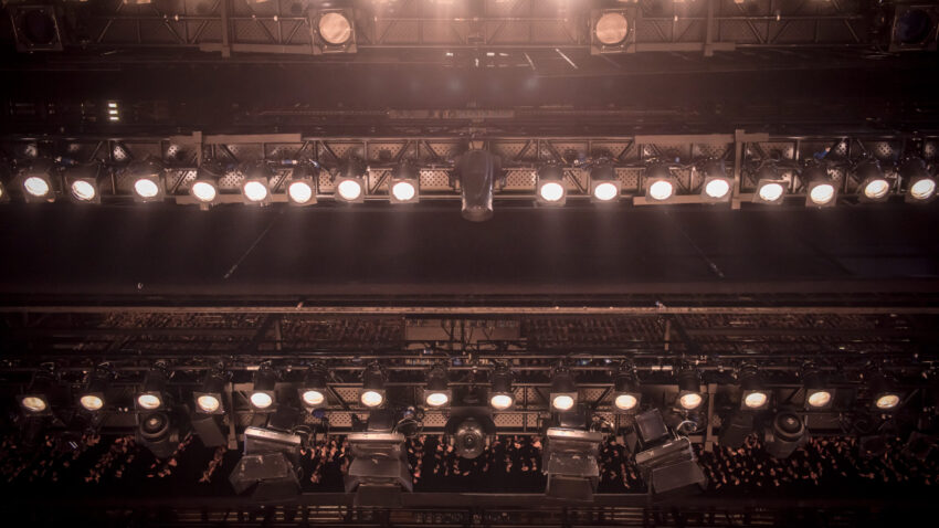 Rows of stage spotlights mounted on overhead metal trusses at the Royal Northern College of Music, with some lights lit.