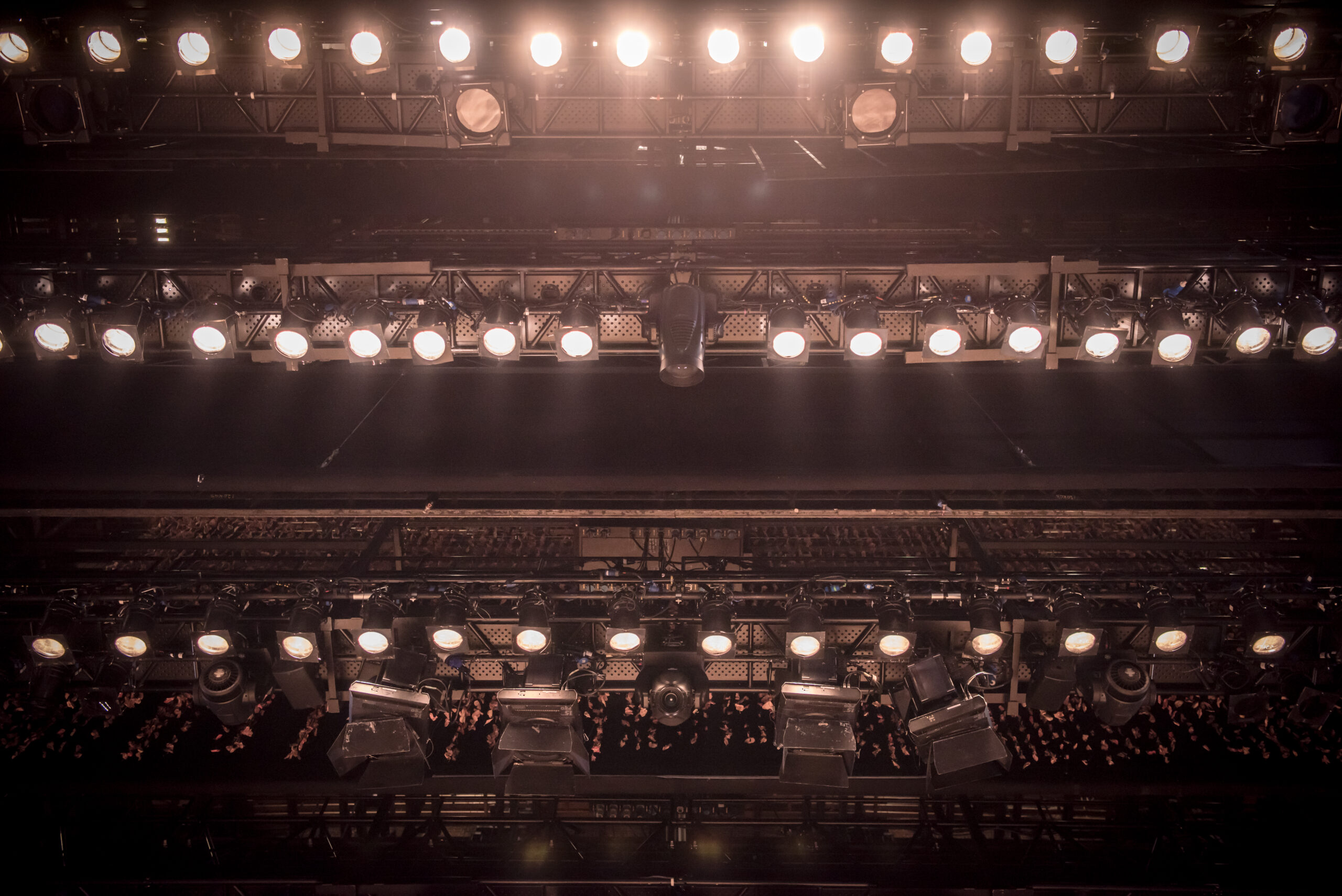 Rows of stage spotlights mounted on overhead metal trusses at the Royal Northern College of Music, with some lights lit.