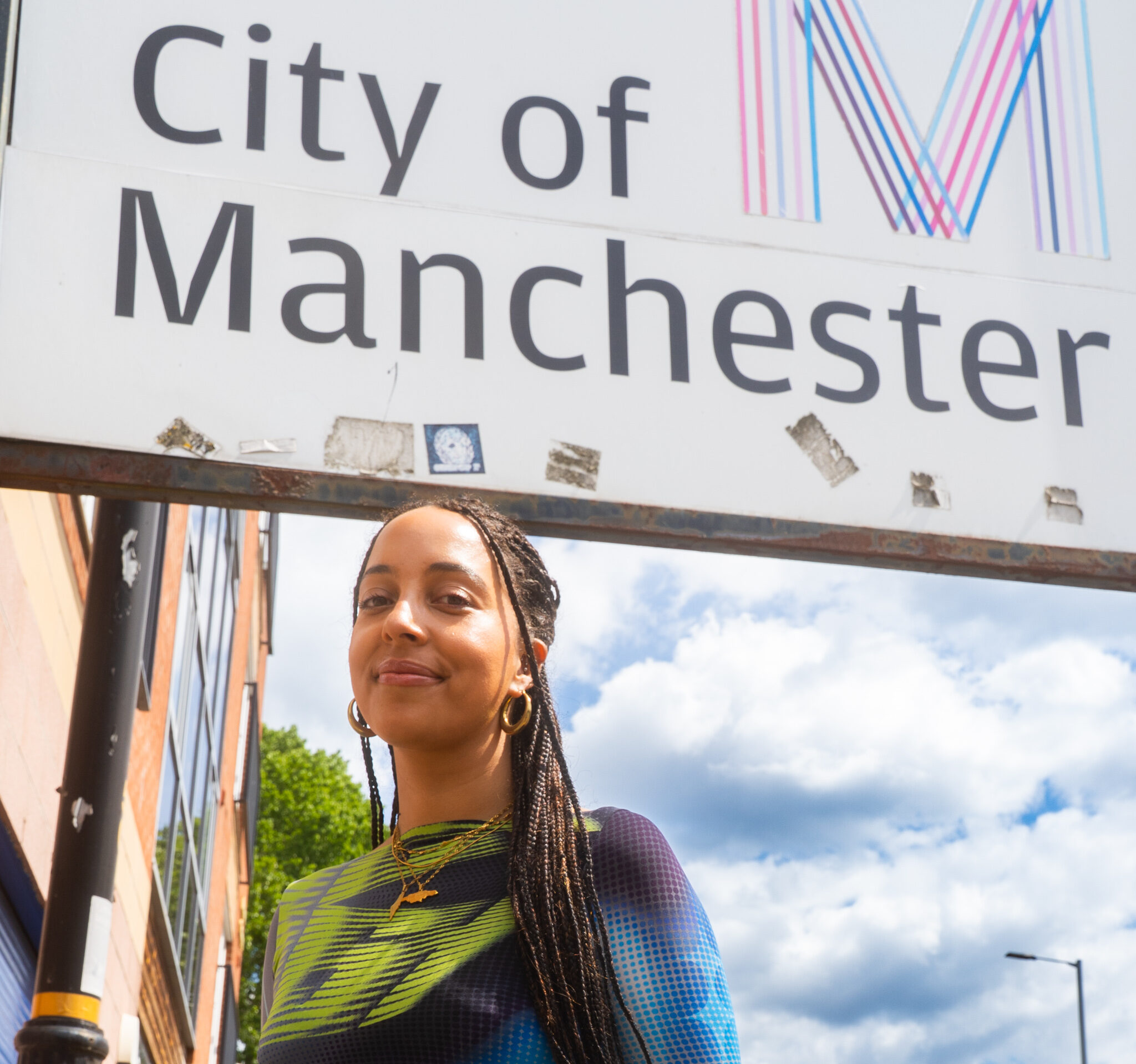 A person stands in front of a City of Manchester sign.
